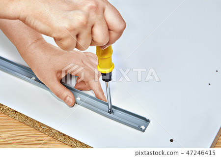 Furniture assembler tightens drawer slide to table 47246415
