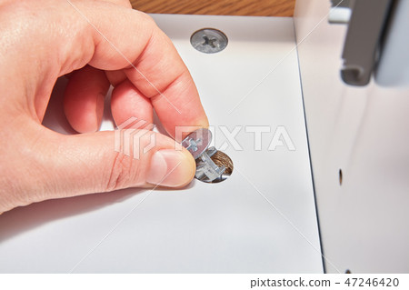 Handyman inserts nut into hole in furniture 47246420