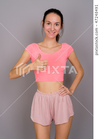 Happy beautiful woman ready for gym against gray background 47248491