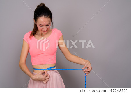Young beautiful woman ready for gym measuring waist Young beautiful woman ready for gym measuring waist 47248501