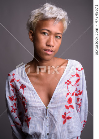 Young beautiful rebellious woman with short hair against gray ba 47248671