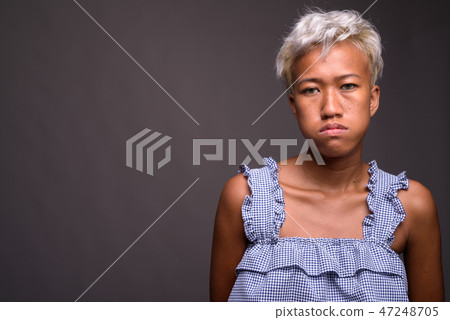 Young beautiful rebellious woman with short hair against gray ba 47248705