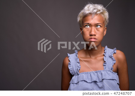 Bored beautiful rebellious woman with short hair against gray ba 47248707