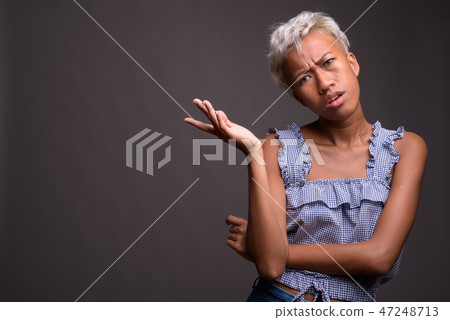 Young beautiful rebellious woman with short hair against gray ba Young beautiful rebellious woman with short hair against gray ba 47248713
