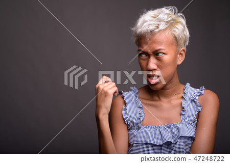 Young beautiful rebellious woman with short hair against gray ba 47248722