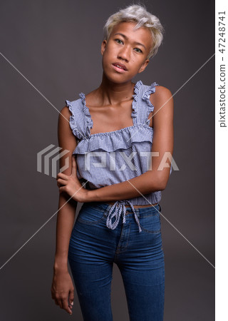 Young beautiful rebellious woman with short hair against gray ba 47248741