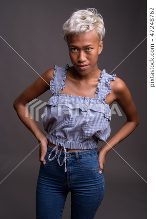 Young beautiful rebellious woman with short hair against gray ba 47248762