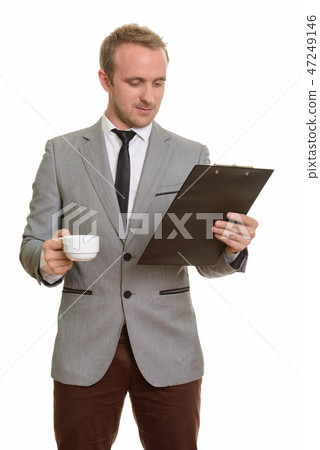 Handsome Caucasian businessman reading clipboard while drinking  47249146