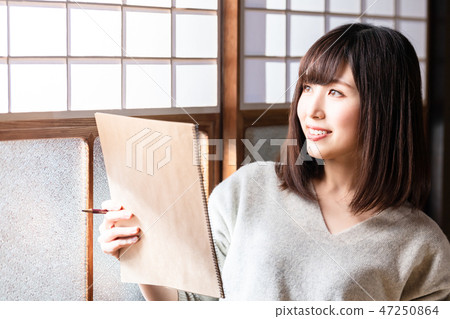 A young woman sketching in an old private house 47250864