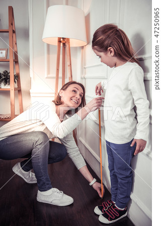 Pleasant nice woman measuring her daughters height 47250965