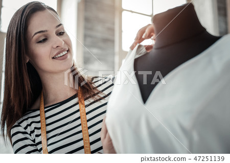 Dark-haired designer making some measurements while sewing dress 47251139