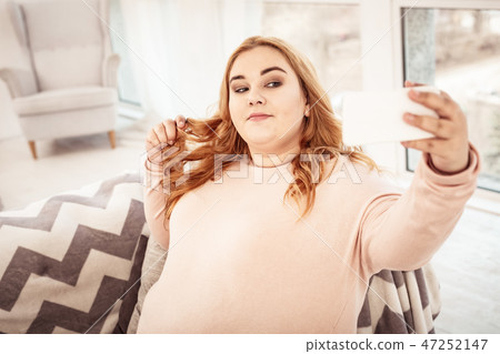 Long-haired ginger body positive woman making selfie with her smartphone Long-haired ginger body positive woman making selfie with her smartphone 47252147