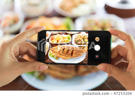 Woman taking a photo of food with smartphone Woman taking a photo of food with smartphone 47253104