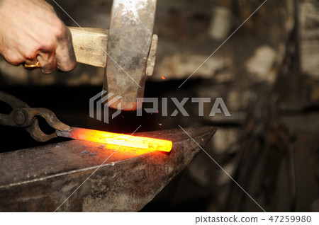 Blacksmith working metal with hammer on the anvil 47259980