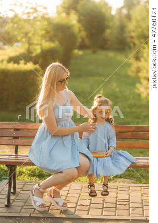 Mom and his little daughter are sitting on a bench in the park 47260123