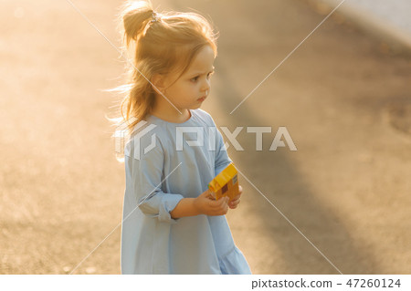Little girl in blue dress walk in park 47260124