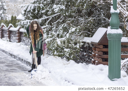 woman clears snow from the road 47265652