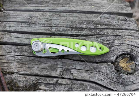 Small green knife on an old wooden stump. Small green knife on an old wooden stump. 47266704