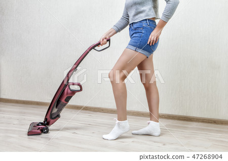 Housemaid cleans dust with modern vacuum cleaner. 47268904