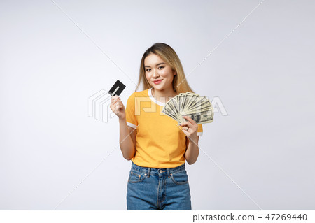 Asian content woman holding fan of money dollar banknotes and credit card and looking on copyspace Asian content woman holding fan of money dollar banknotes and credit card and looking on copyspace 47269440