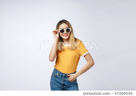 Young happy Asian woman smiling in fashionable dress and sunglasses and summer hat over Young happy Asian woman smiling in fashionable dress and sunglasses and summer hat over 47269593