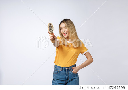 young beautiful woman combing her hair isolated over grey background. young beautiful woman combing her hair isolated over grey background. 47269599