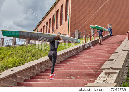 Athletes walk upstairs with kayaks on shoulders 47269789