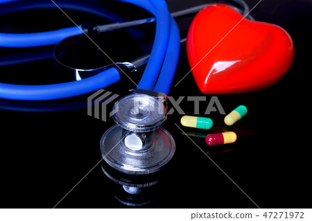 stethoscope, Red heart and assorted pils on black mirror background. Selective focus. 47271972