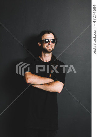 Casual man with dreadlocks standing on a black background. 47274694