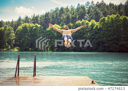 Young fit man making a jump into a lake. Young fit man making a jump into a lake. 47274813