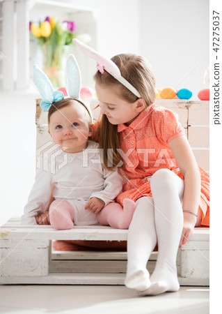 Sibiling in funny bunny ears sitting together. Sibiling in funny bunny ears sitting together. 47275037