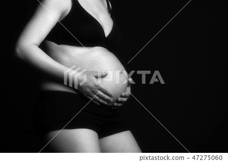 Pregnant woman sitting, touching her belly. 47275060
