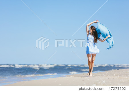Young girl walking on the beach with blue scarf Young girl walking on the beach with blue scarf 47275202