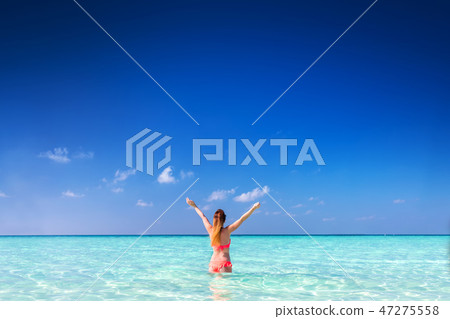 Beautiful young woman standing in the ocean with hands raised. Maldives Beautiful young woman standing in the ocean with hands raised. Maldives 47275558