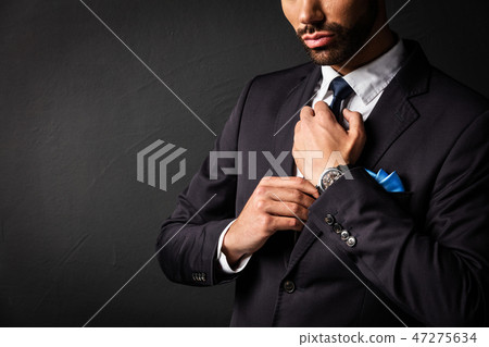 Attractive businessman fixing his tie. Attractive businessman fixing his tie. 47275634