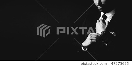Young man in dark suit fixing his tie. Young man in dark suit fixing his tie. 47275635