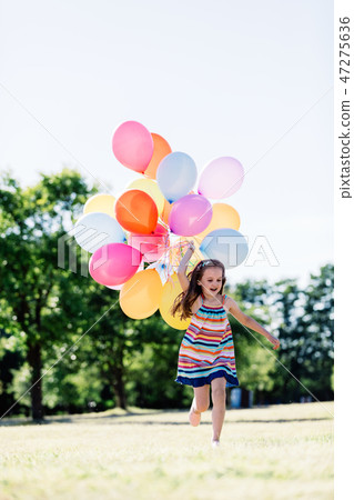 Happy girl in running with a bunch of balloons Happy girl in running with a bunch of balloons 47275636