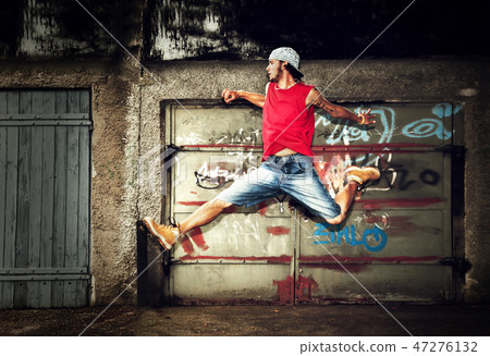 Young man jumping on grunge wall Young man jumping on grunge wall 47276132
