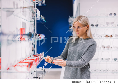 Woman choosing glasses at optics. 47276314