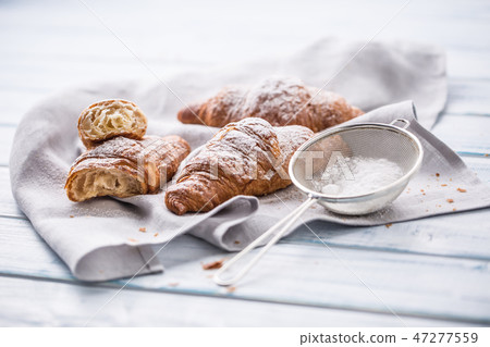Fresh buttery croissants sprinkled with sugar. 47277559