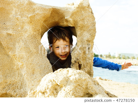 little cute boy on sea coast thumbs up playing with rocks 47278150