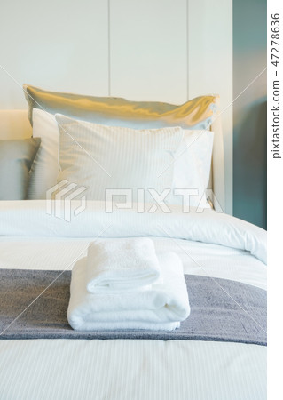 Clean white towels setting on bed in bedroom 47278636