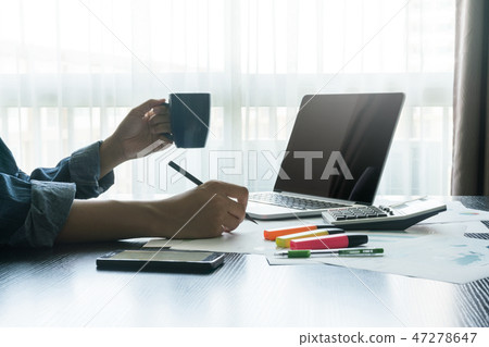 businessman writing a plan and holding coffee cup 47278647