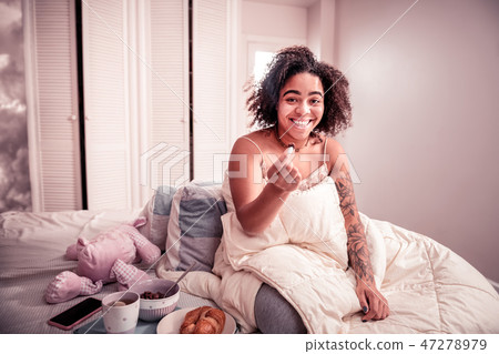 Smiling cheerful lady with curly hair carrying chocolate cereal Smiling cheerful lady with curly hair carrying chocolate cereal 47278979