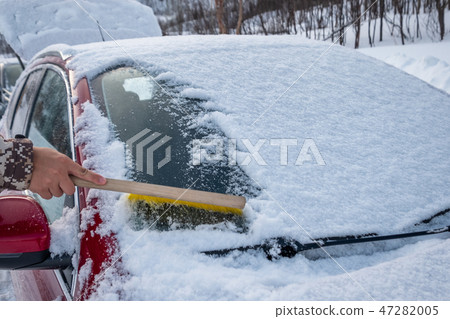 Hand using brush sweeping snow on car windscreen 47282005