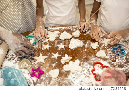 Father and daughters standing near table after forming cookies 47284328