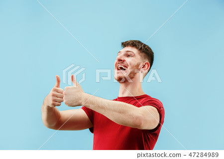 The happy businessman standing and smiling against blue background. 47284989