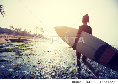 Woman surfer walking with surfboard on coral reefs 47285228