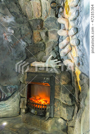 A fireplace made in the wall made of stone. With a A fireplace made in the wall made of stone. With a 47285364