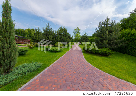 The path in the park is laid out with red tiles be The path in the park is laid out with red tiles be 47285659